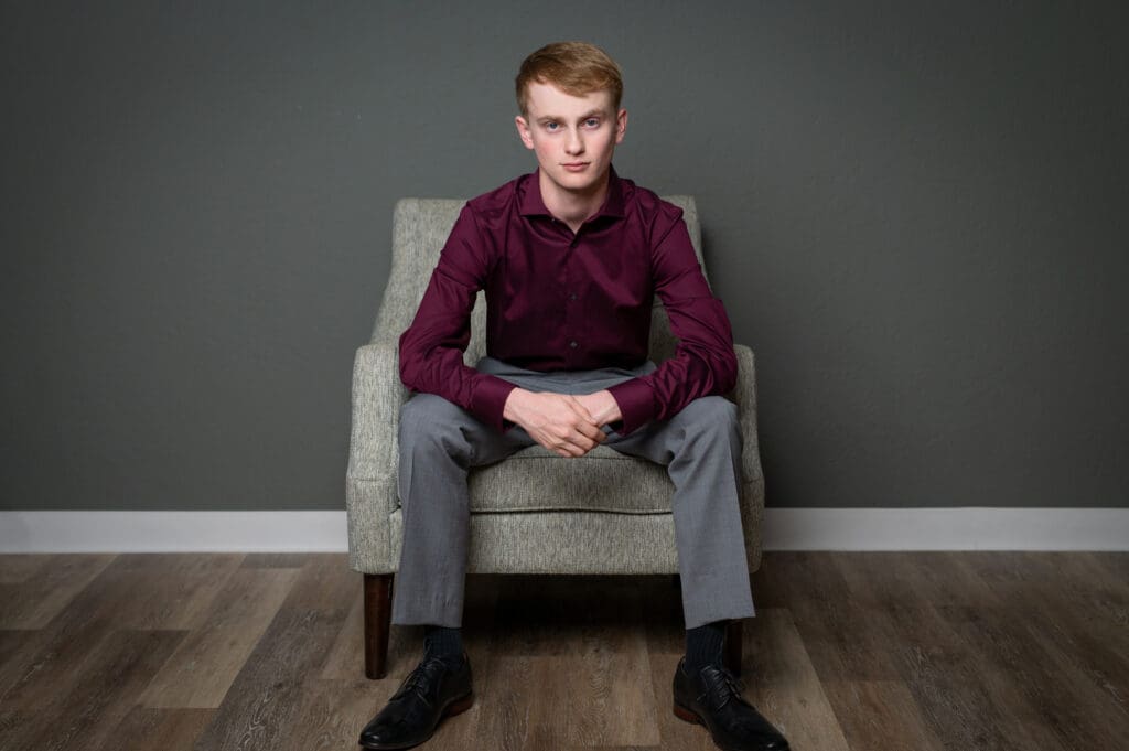 Senior picture of a graduate posing with confidence, High school senior smiling in formal attire